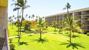 A hotel with a large building, a well-maintained lawn, and several palm trees. - Maui Sunset - Maui Condo & Home (Kihei)