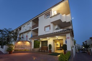 A hotel with a brick facade, a balcony, and a well-lit entrance.