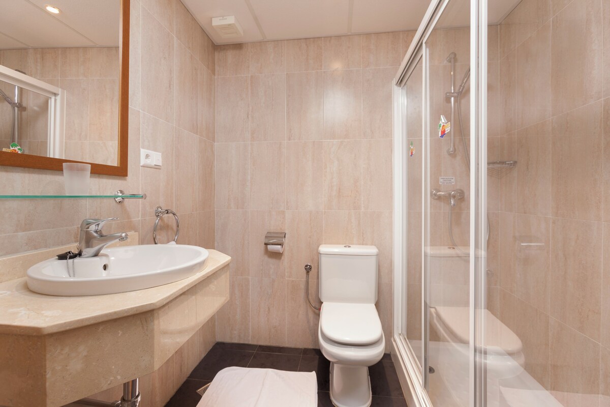 A modern bathroom with a glass shower enclosure, a white sink, and a toilet.