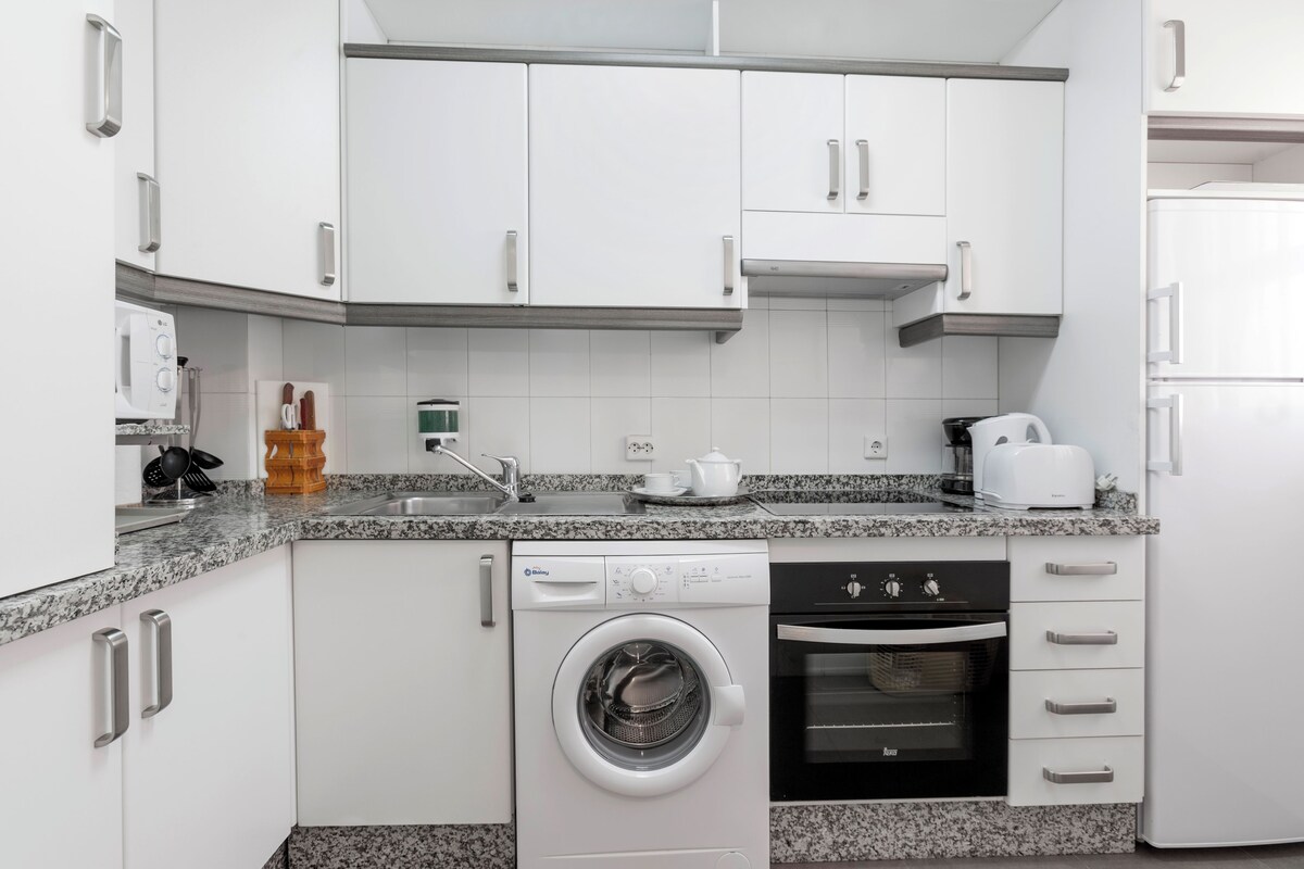 A modern kitchen with white cabinets, a built-in washing machine, and a toaster.