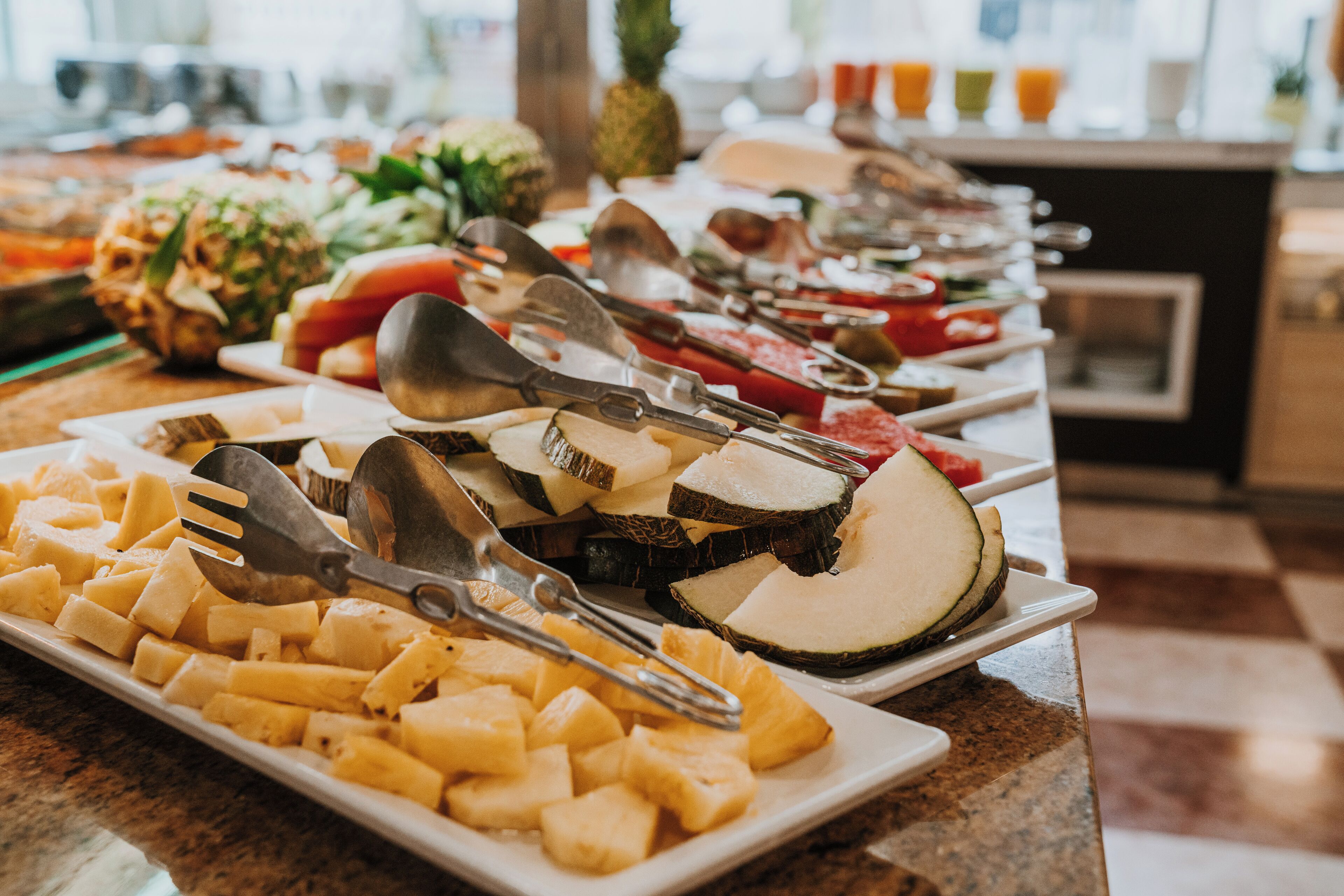 A buffet with various fruits and vegetables, including pineapple, watermelon, and cheese.