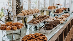Un bufé con diversas opciones de panadería, incluyendo pasteles y panes.