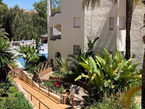 A multi-level outdoor area with a staircase, surrounded by lush greenery and palm trees. - Crown Resorts Club Marbella (Mijas)