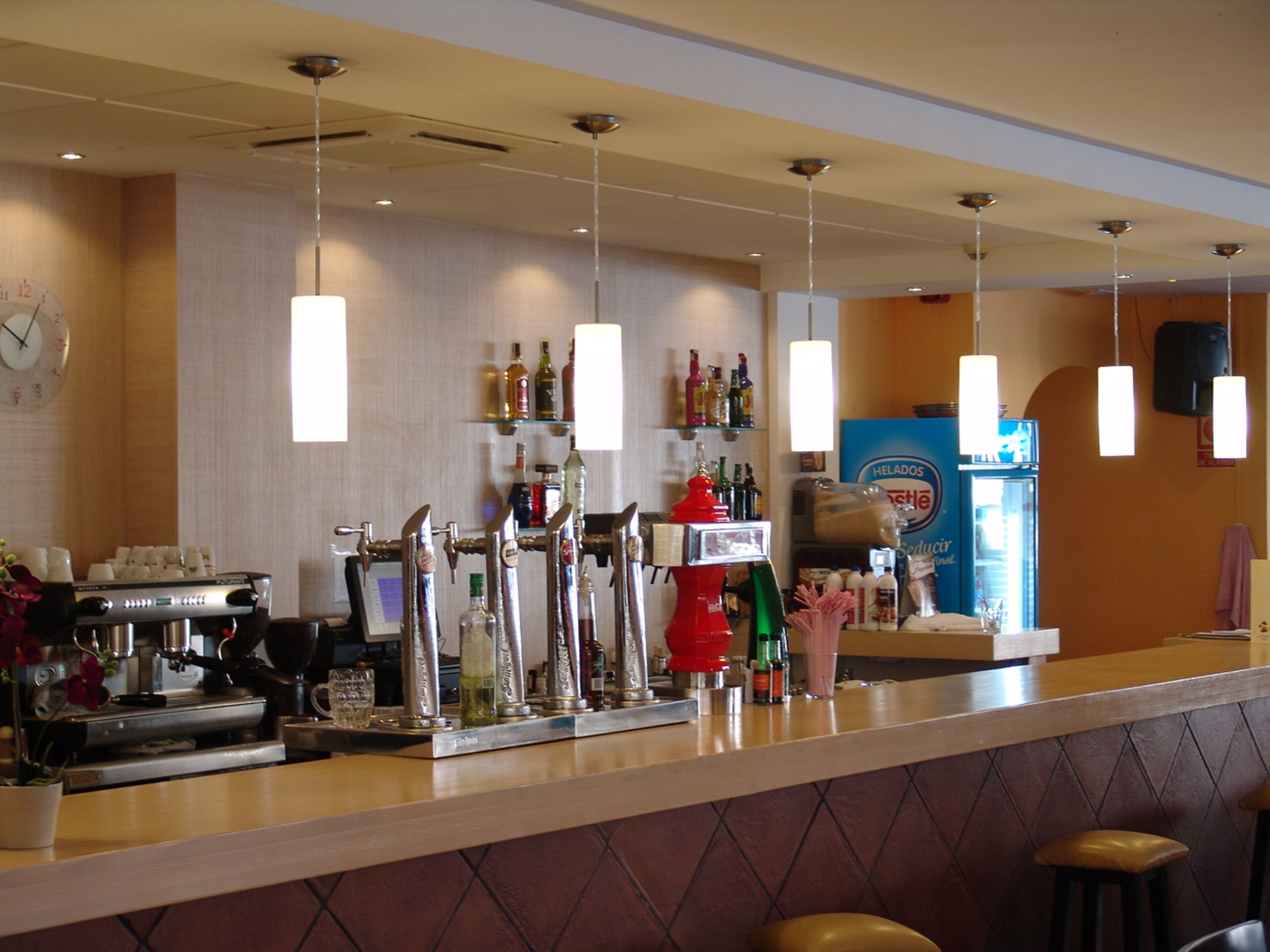 A bar area with multiple taps, a clock, and a refrigerator.