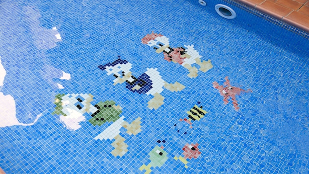 Una piscina con mosaicos que incluyen personajes diversos y un diseño de estrella de mar.