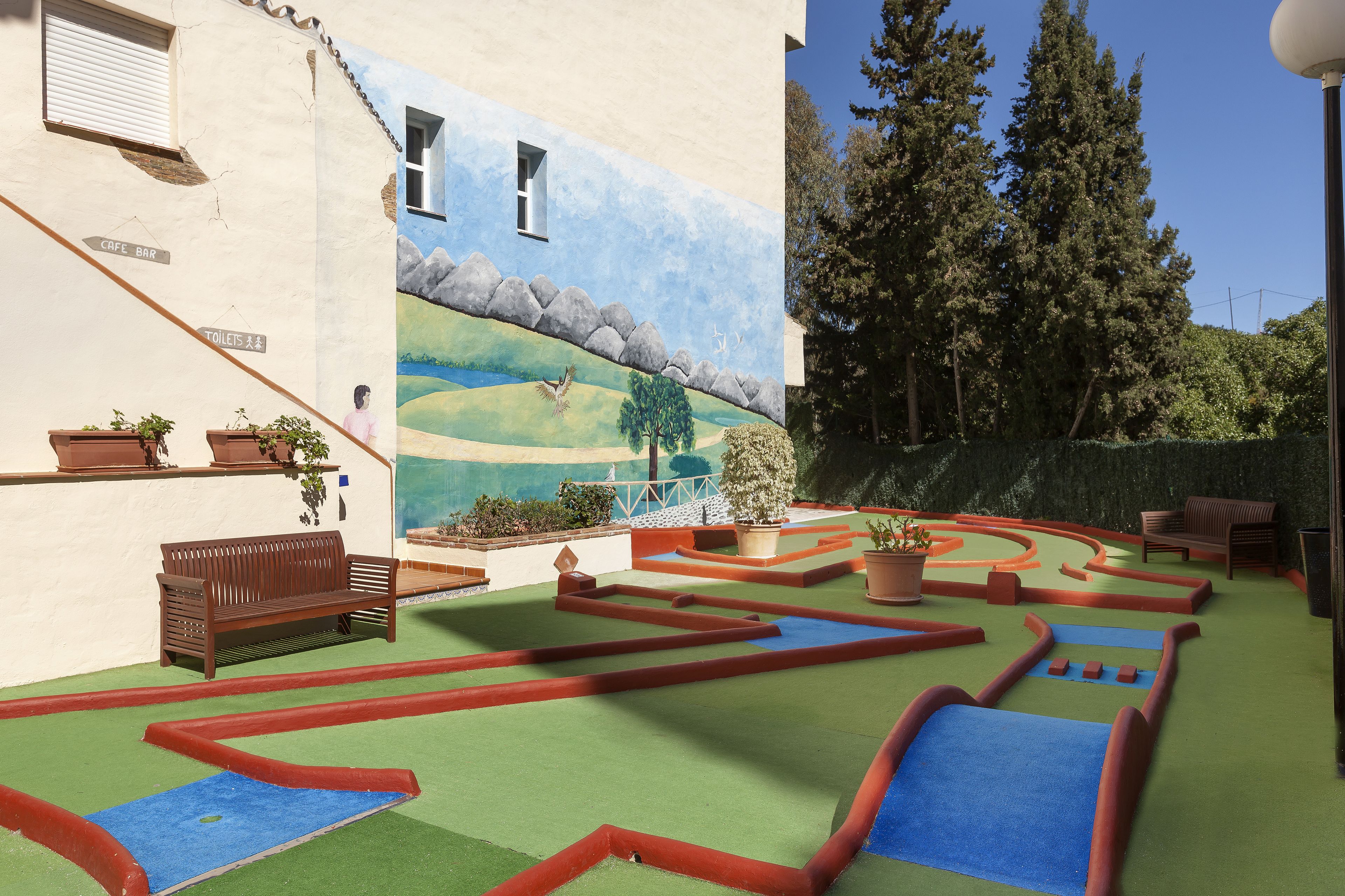 A courtyard with a mural, benches, and a maze-like garden.