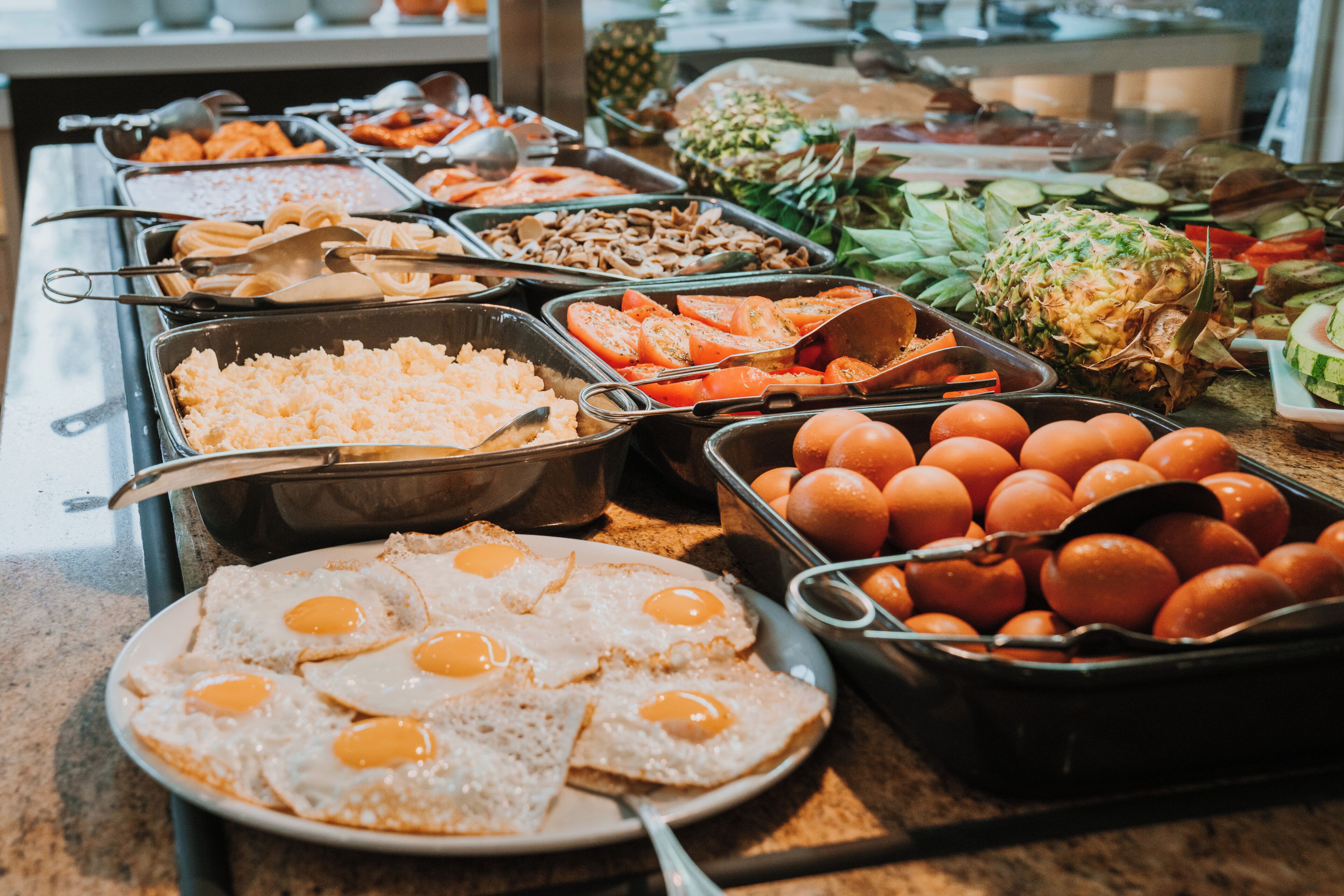 Un bufé con diversas opciones de comida, como huevos, frutas y verduras.