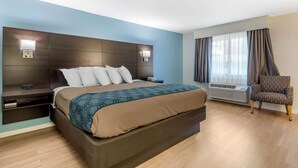A hotel room with a large bed, bedside tables, a chair, and a window with curtains. - Quality Inn & Suites Lincoln I-93 (Lincoln)