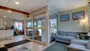 A modern hotel lobby with a dining area, a sofa, and a large window with a view of the outdoors. - Quality Inn & Suites Lincoln I-93 (Lincoln)