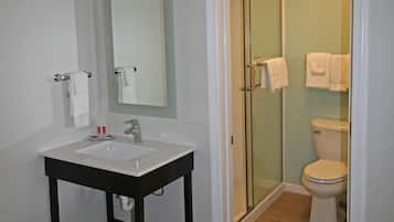 A bathroom with a white sink, mirror, and toilet.