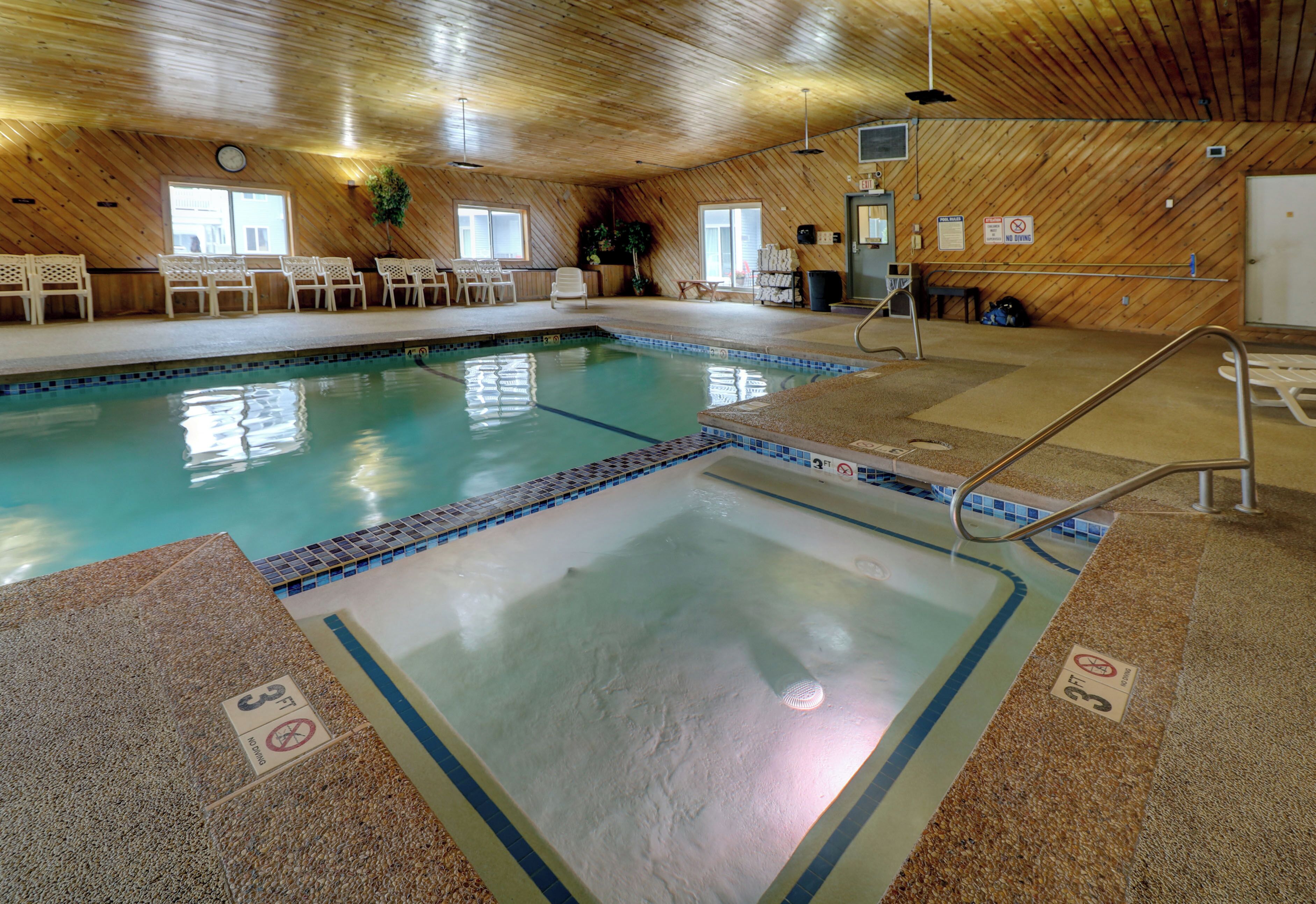 An indoor swimming pool with a wooden ceiling and tiled floor.