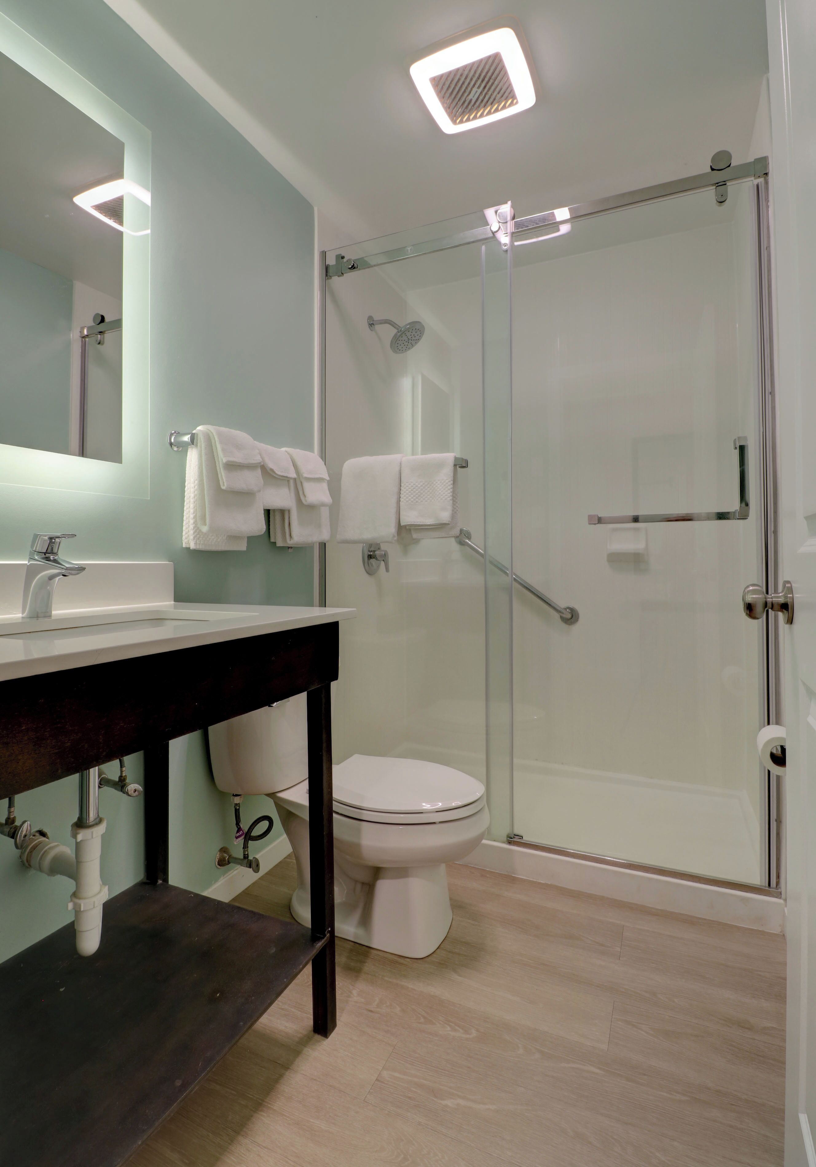 A modern bathroom with a glass-enclosed shower, a white toilet, and a dark wooden vanity.