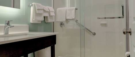 A modern bathroom with a glass-enclosed shower, a white toilet, and a dark wooden vanity.