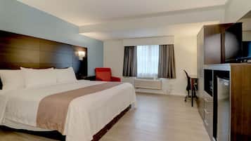 Una habitación de hotel con una cama grande, una silla roja, un televisor y un minibar.