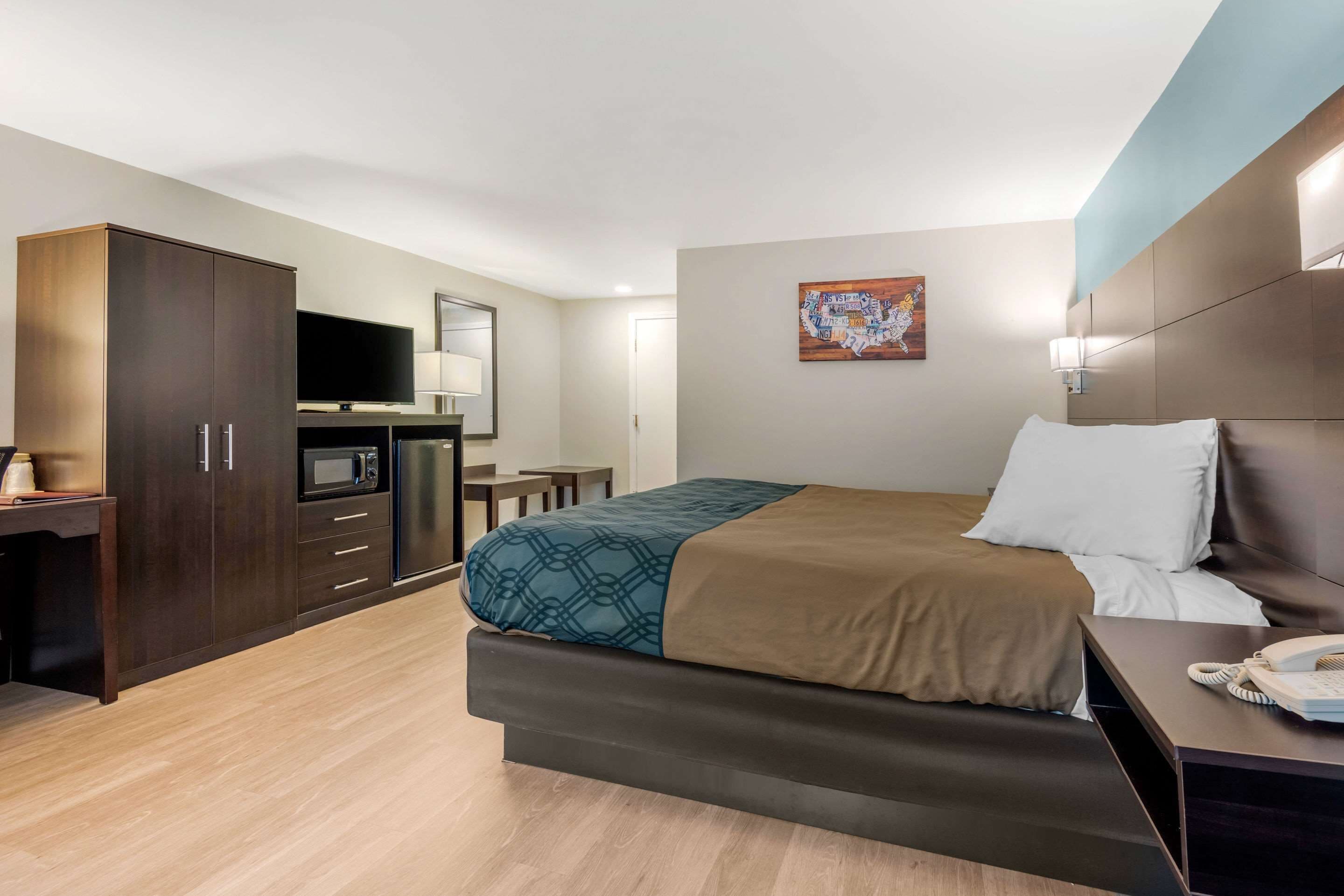 Habitación de hotel con cama, escritorio con computadora, televisor y kitchenette.