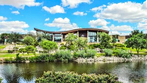 A modern building with a curved roof, surrounded by a well-maintained garden and a pond. - Fairfield Inn & Suites by Marriott San Angelo (San Angelo)