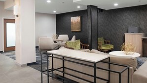 A modern hotel lobby with a sofa, chairs, a coffee table, and a desk. - Fairfield Inn & Suites by Marriott San Angelo (San Angelo)