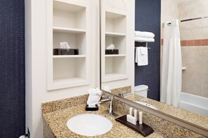 A bathroom with a granite countertop, a white sink, a mirror, and a shower area. - Fairfield Inn & Suites by Marriott San Angelo (San Angelo)