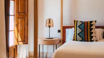 Un dormitorio con cama con dosel, una mesita de noche con lámpara y una puerta de madera con cortinas.