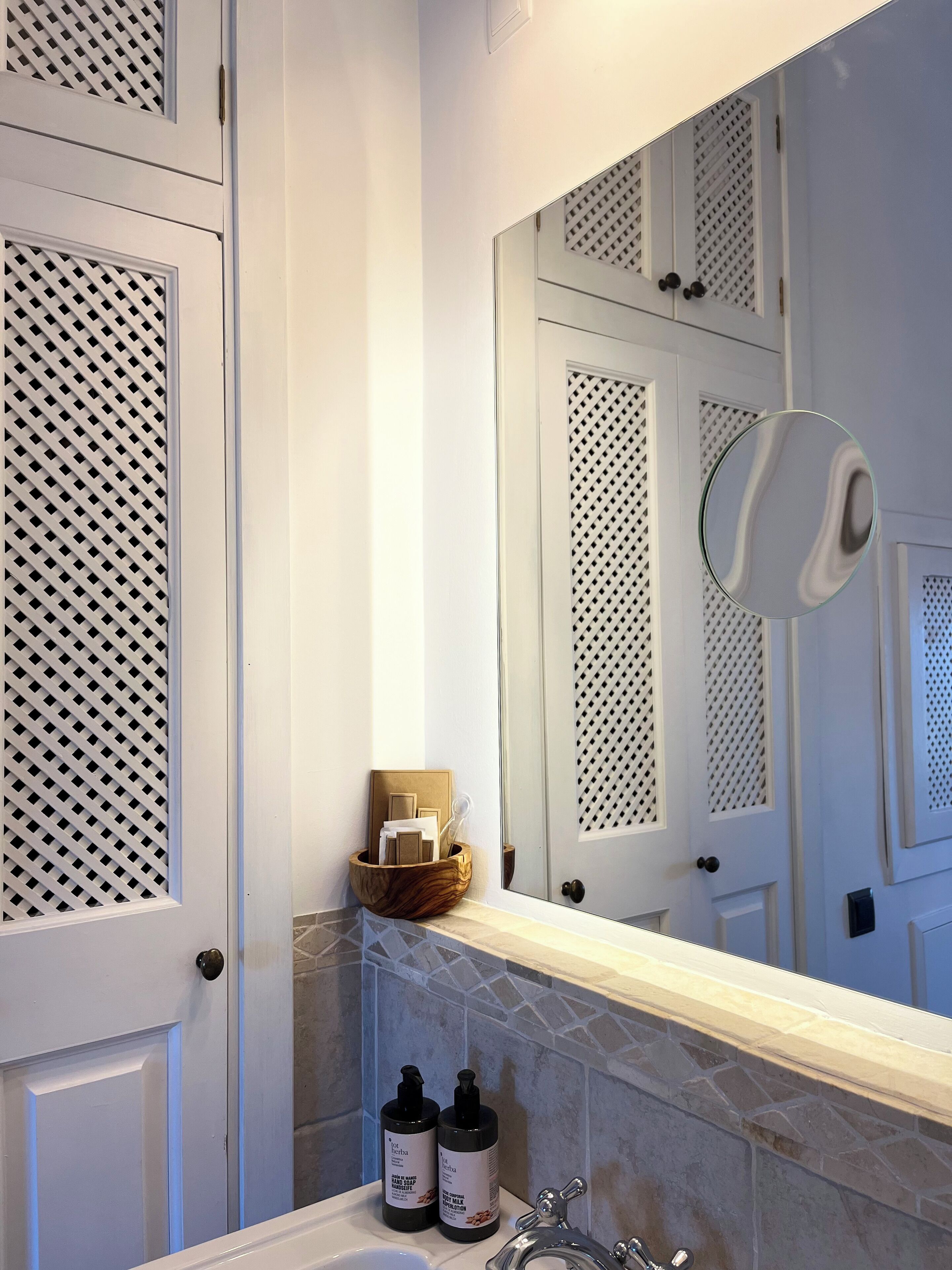 Une salle de bain avec une porte blanche, un miroir, un lavabo et des articles de toilette.