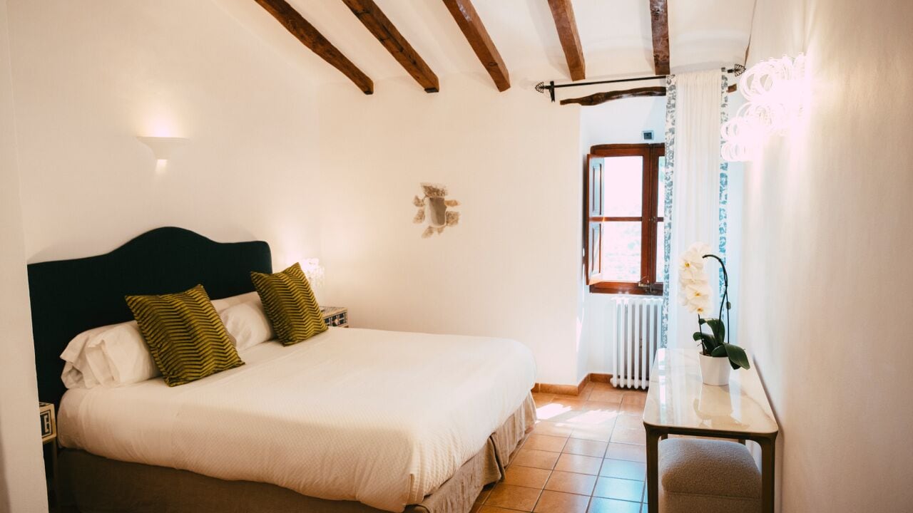 Une chambre à coucher avec un lit, une table de chevet, une fenêtre et un radiateur.