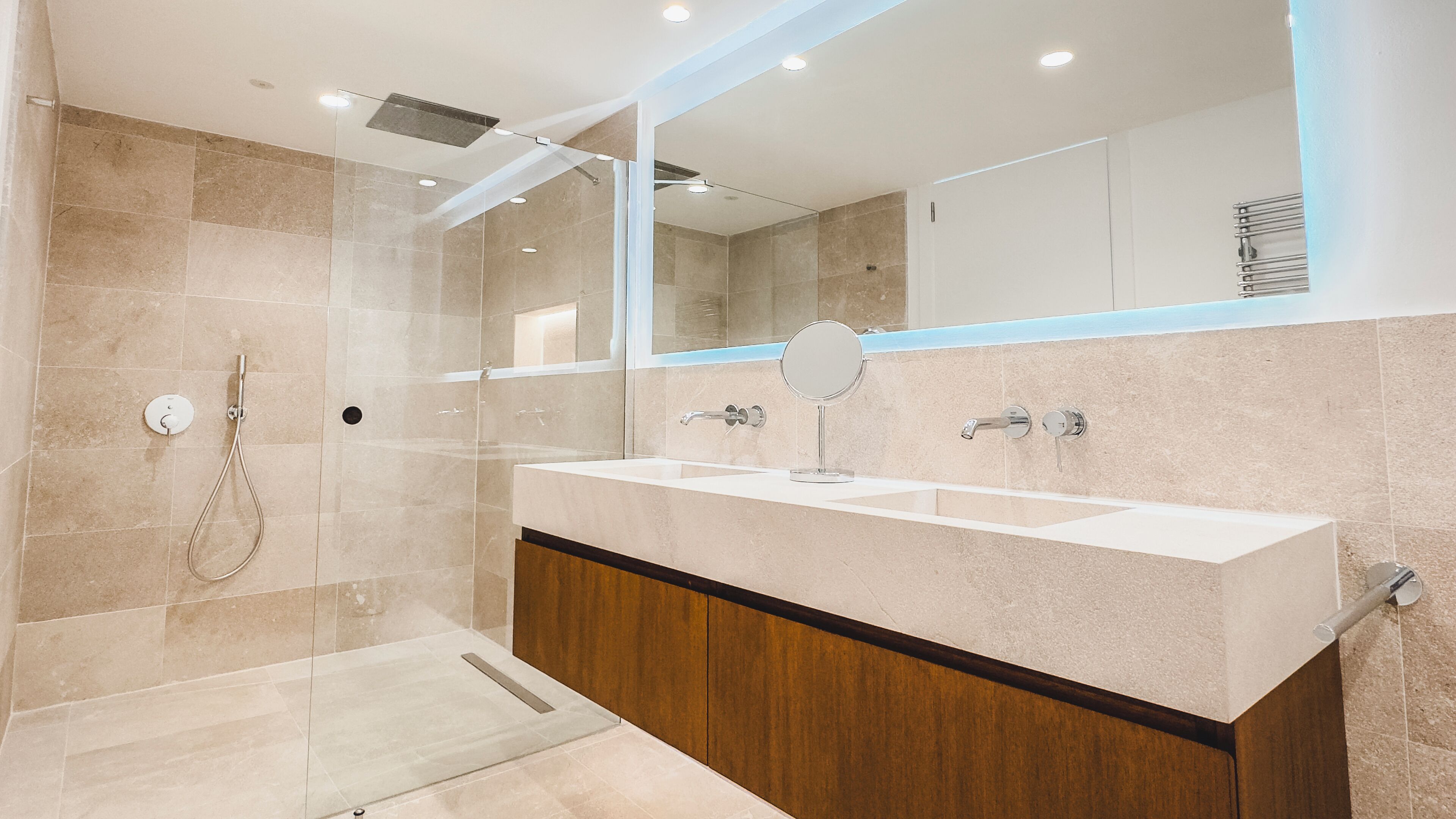 Un baño moderno con cabina de ducha de vidrio, tocador doble y un espejo grande.