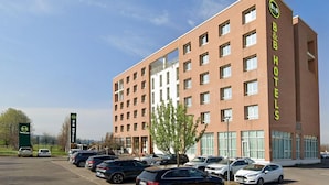Un hôtel de type « bed and breakfast » doté d’une façade moderne en briques, de nombreuses fenêtres et d’un parking où sont stationnées plusieurs voitures.