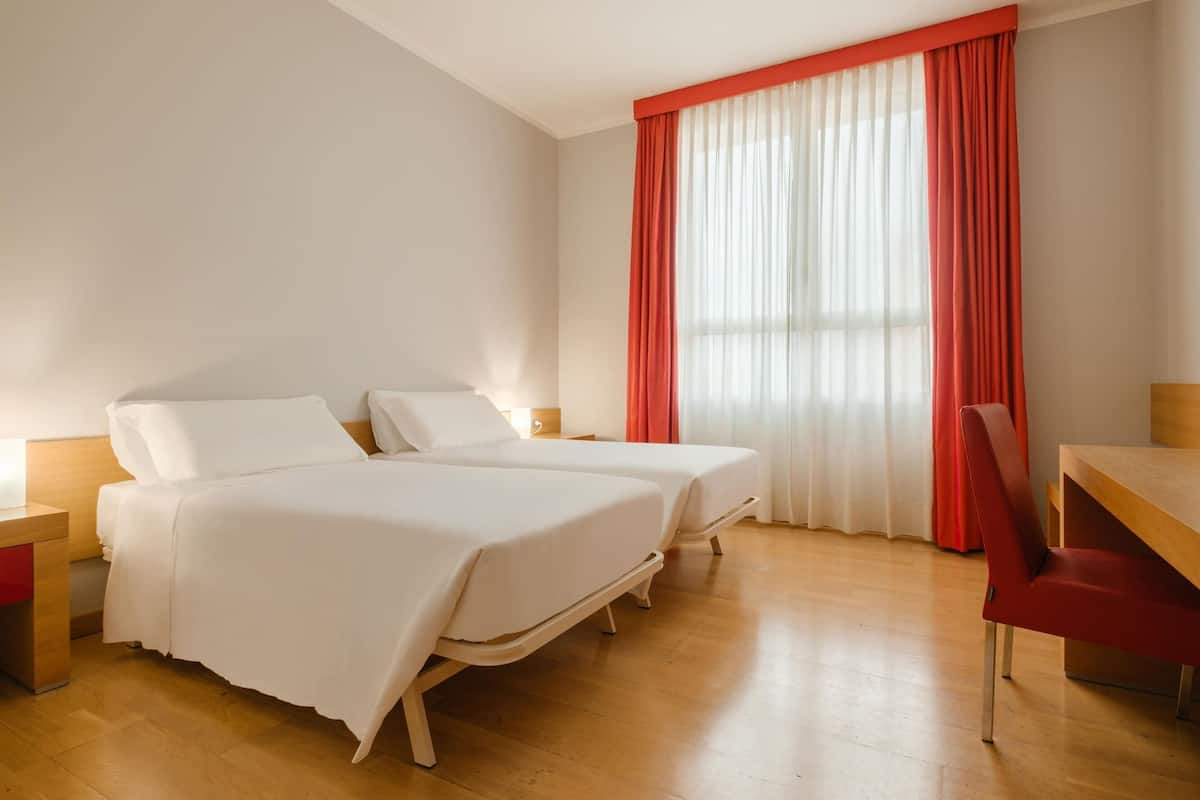 Una habitación de hotel con dos camas, un escritorio y una silla.