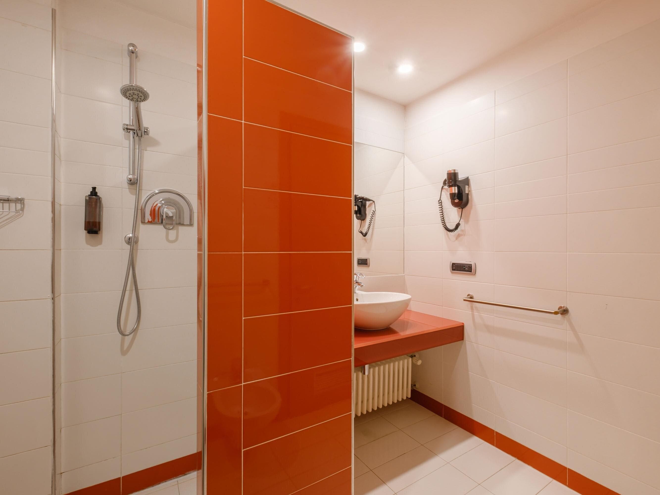 Un baño con ducha, lavamanos y un perchero para toallas.