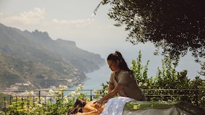 A massage therapy session taking place outdoors with a scenic view of mountains and a body of water in the background.