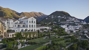 A hillside town with terraced houses and a prominent white building with arched windows.