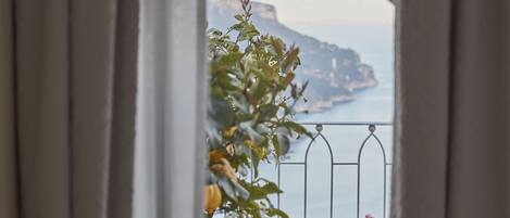 Vista desde una ventana con balcón, mostrando un paisaje costero con acantilados y el mar.