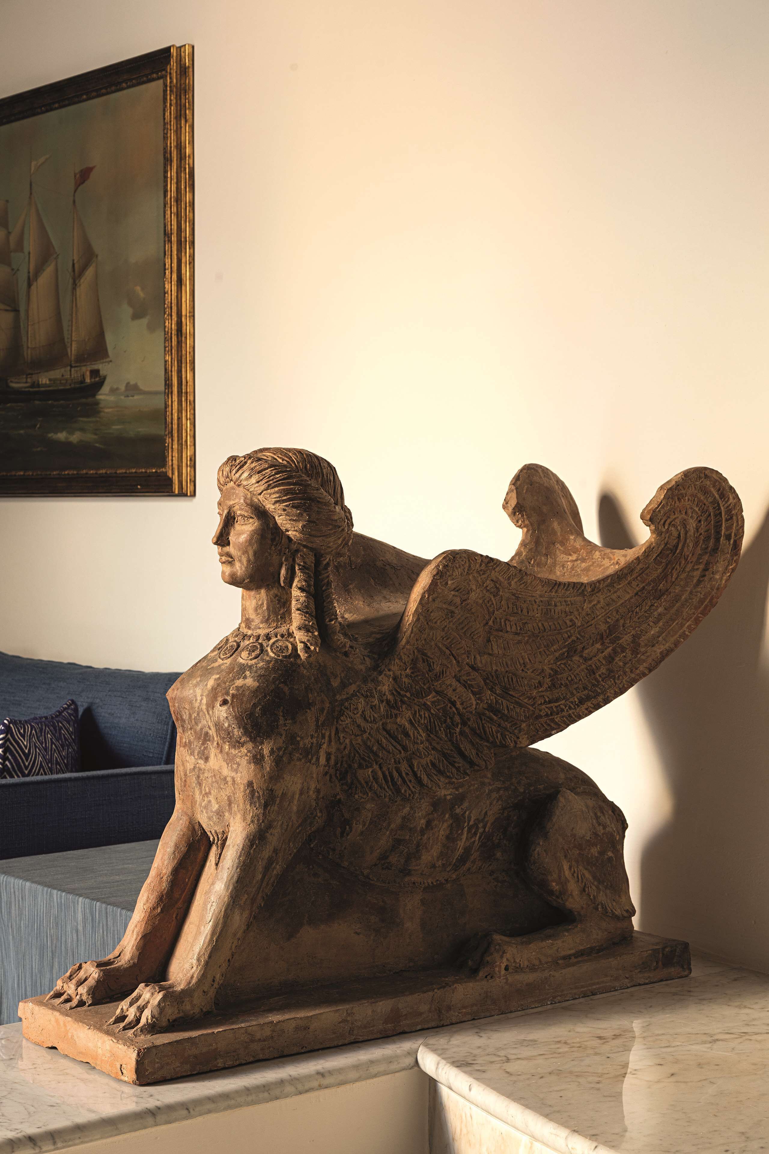 Eine Skulptur einer sitzenden Figur mit Flügeln auf einer Marmorplatte.