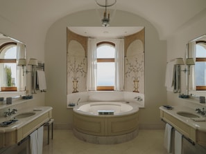 A spacious bathroom with a large bathtub, two sinks, and a vanity.