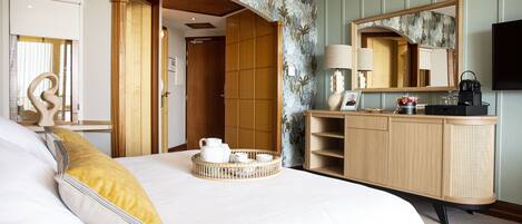 A hotel room with a bed, a bedside table with a lamp, a dresser, and a mirror.