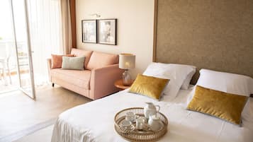 Habitación de hotel con cama, sofá y zona de comedor con una bandeja de té.