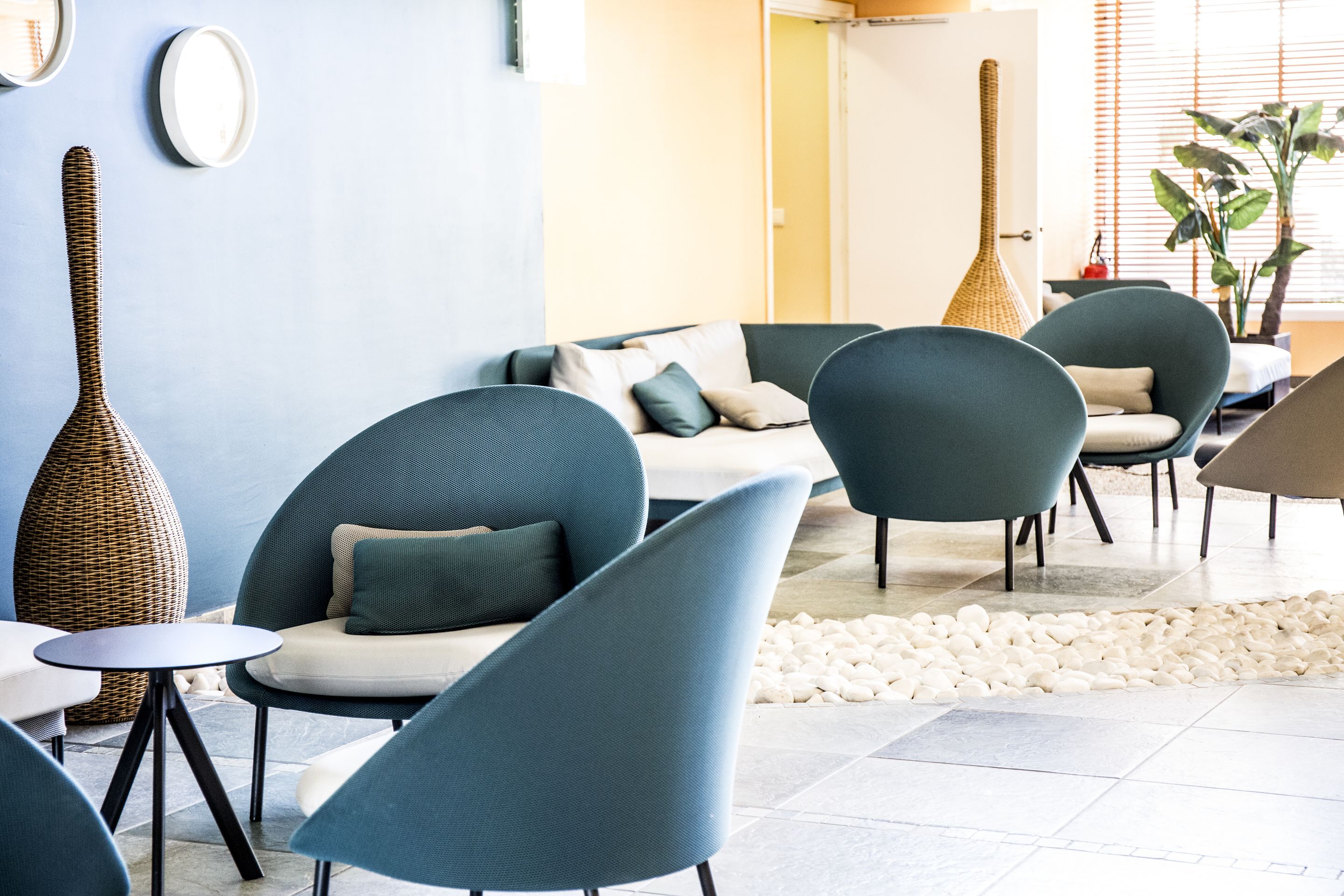 Eine moderne Lounge mit bequemen Sitzmöglichkeiten, einer großen Vase und einer Pflanze.