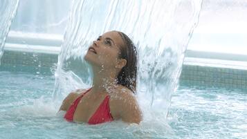 A person in a swimming pool with water cascading over them.