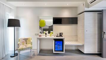 Una habitación de hotel moderna con un escritorio blanco, una silla, una cafetera y un mini refrigerador integrado.