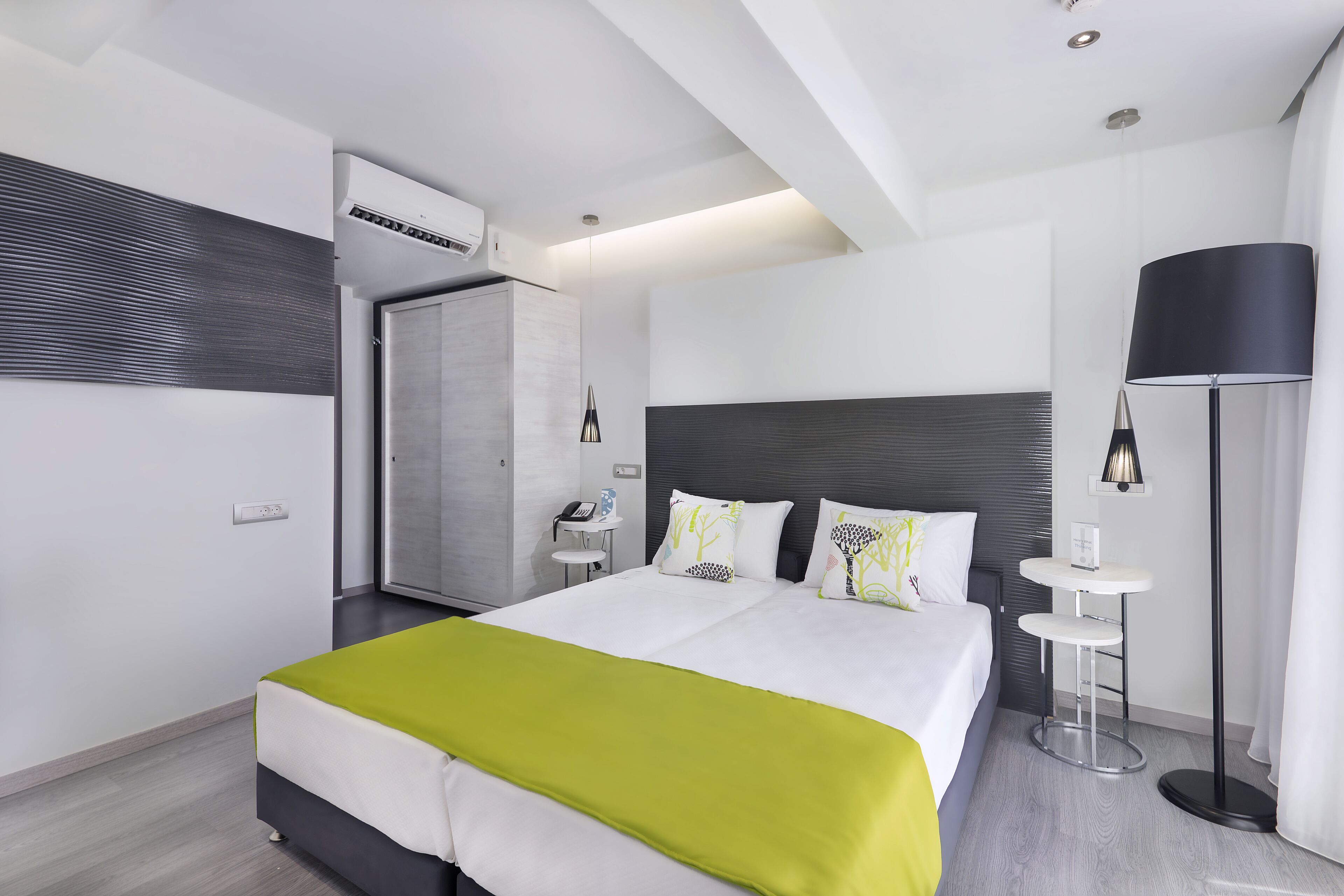 Une chambre d’hôtel moderne, dotée d’un grand lit, de tables de chevet, d’un bureau et d’une armoire.