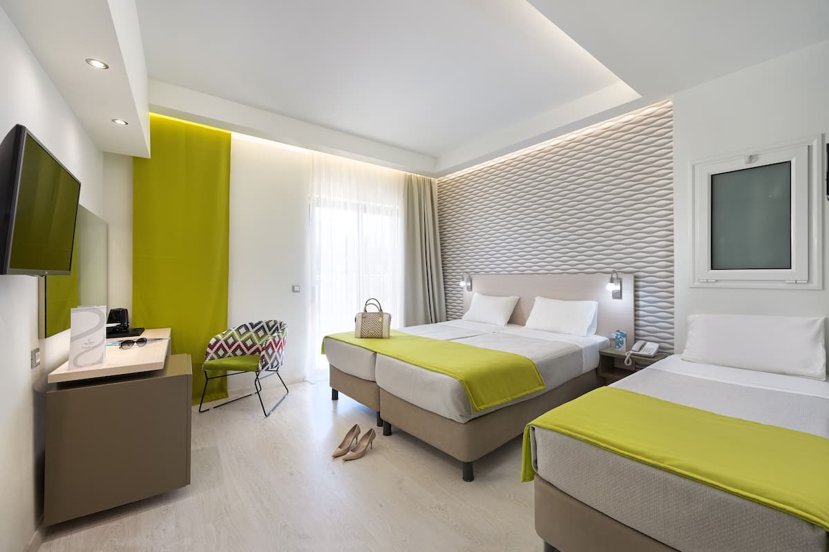 A modern hotel room with a bed, a desk, a chair, and a TV.