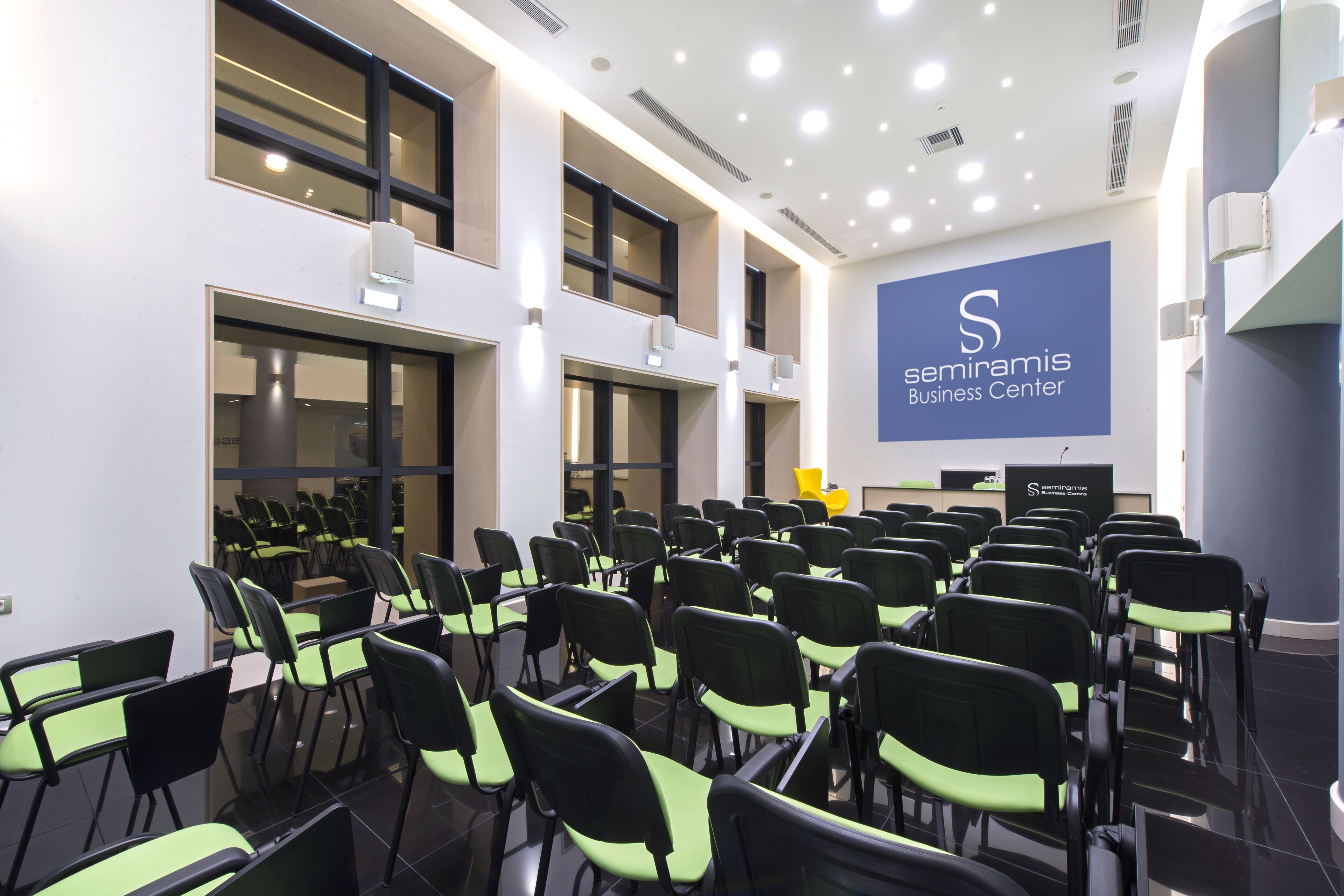 Un salón de conferencias con filas de sillas y una pantalla grande que muestra 'seminamis Business Center'.