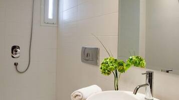 Une salle de bain moderne avec un lavabo blanc, un miroir et une douche.