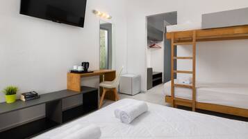 A modern hotel room with a bunk bed, a desk with a chair, a television, and a small plant.