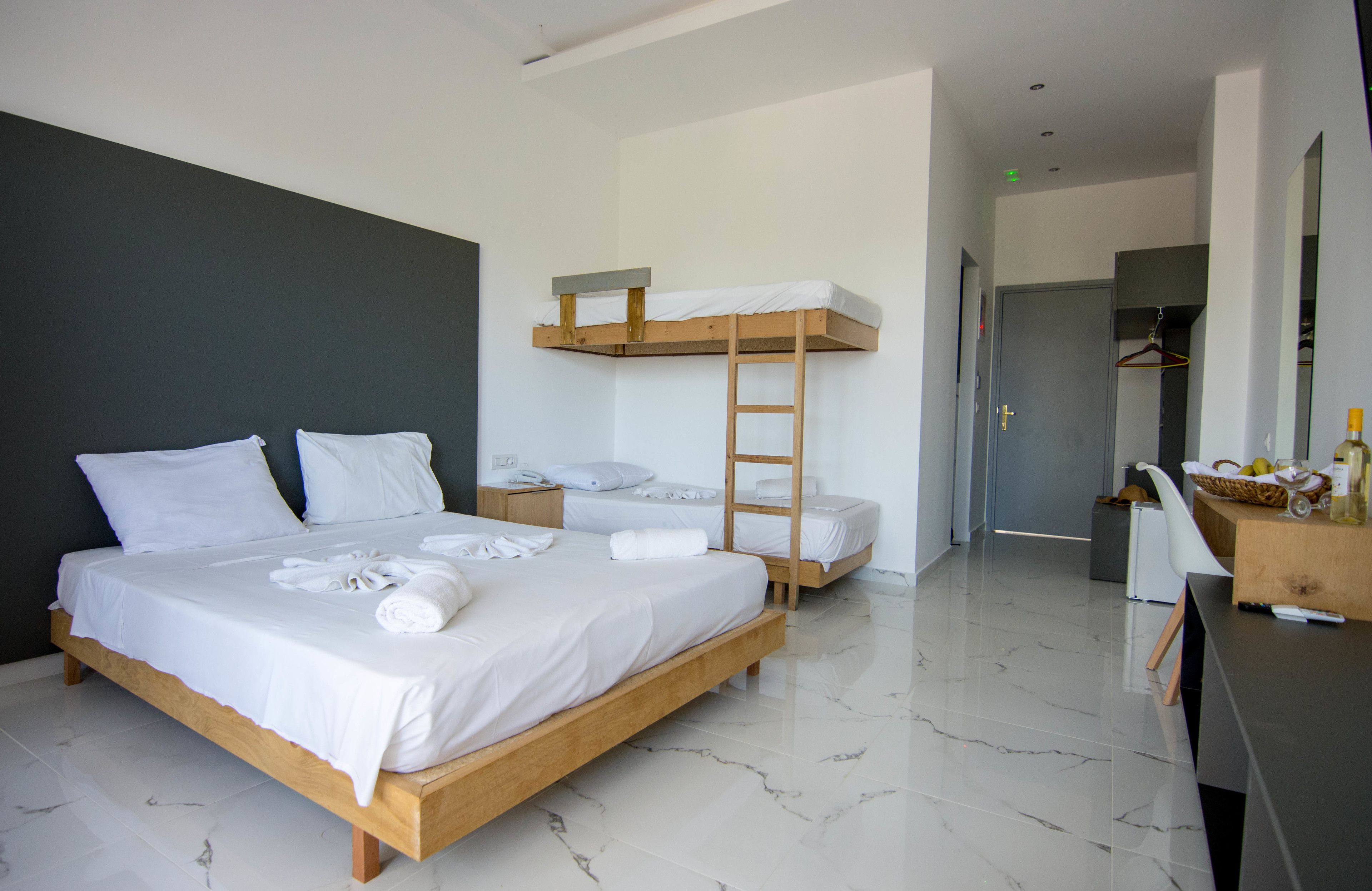 Ein modernes Schlafzimmer mit einem großen Bett, einem Schlafplatz in Etagenbetten, einer Holzleiter, einem Schreibtisch mit Stuhl und einem Spiegel.