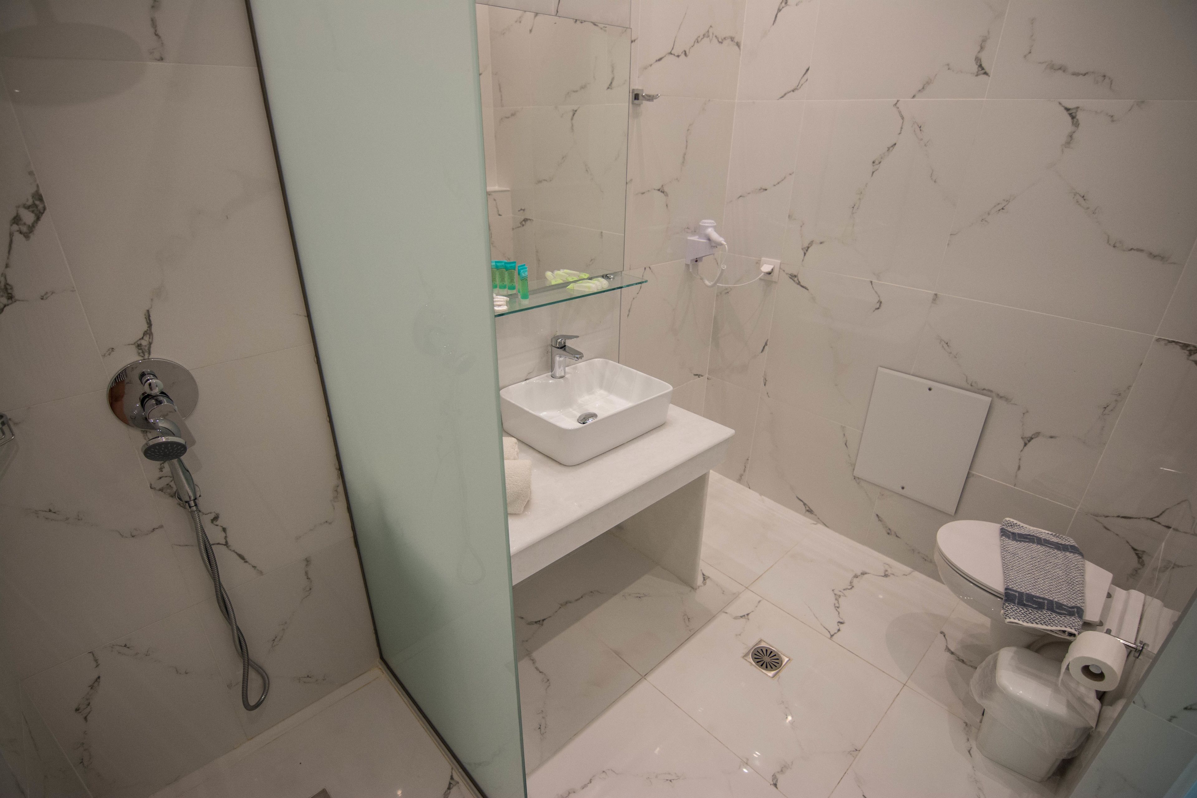 Une salle de bain avec une douche à parois de verre, un lavabo blanc et des toilettes.