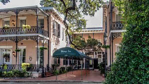 A historic building with a covered entrance, ornate balconies, and hanging plants.