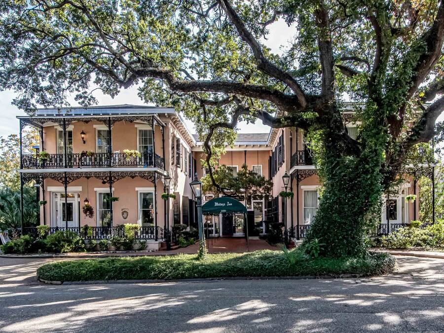 A two-story building with a balcony, a covered entrance, and a well-maintained garden.