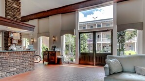 A spacious living area with a brick fireplace, a light blue sofa, and large windows offering a view of the outdoors.