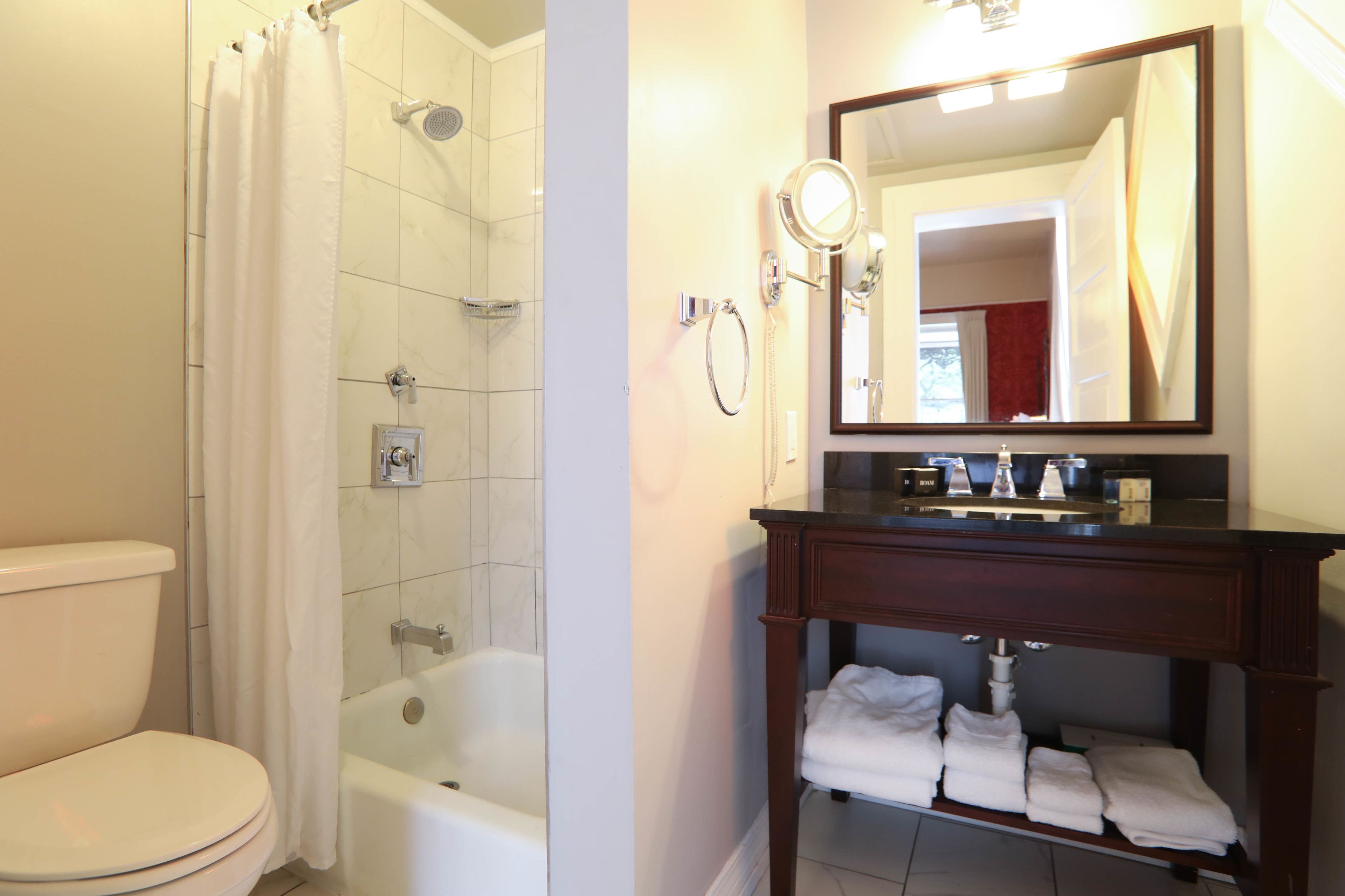 A bathroom with a shower, toilet, bathtub, and a vanity with a mirror and towel rack.